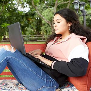 student sitting on bench using a laptop